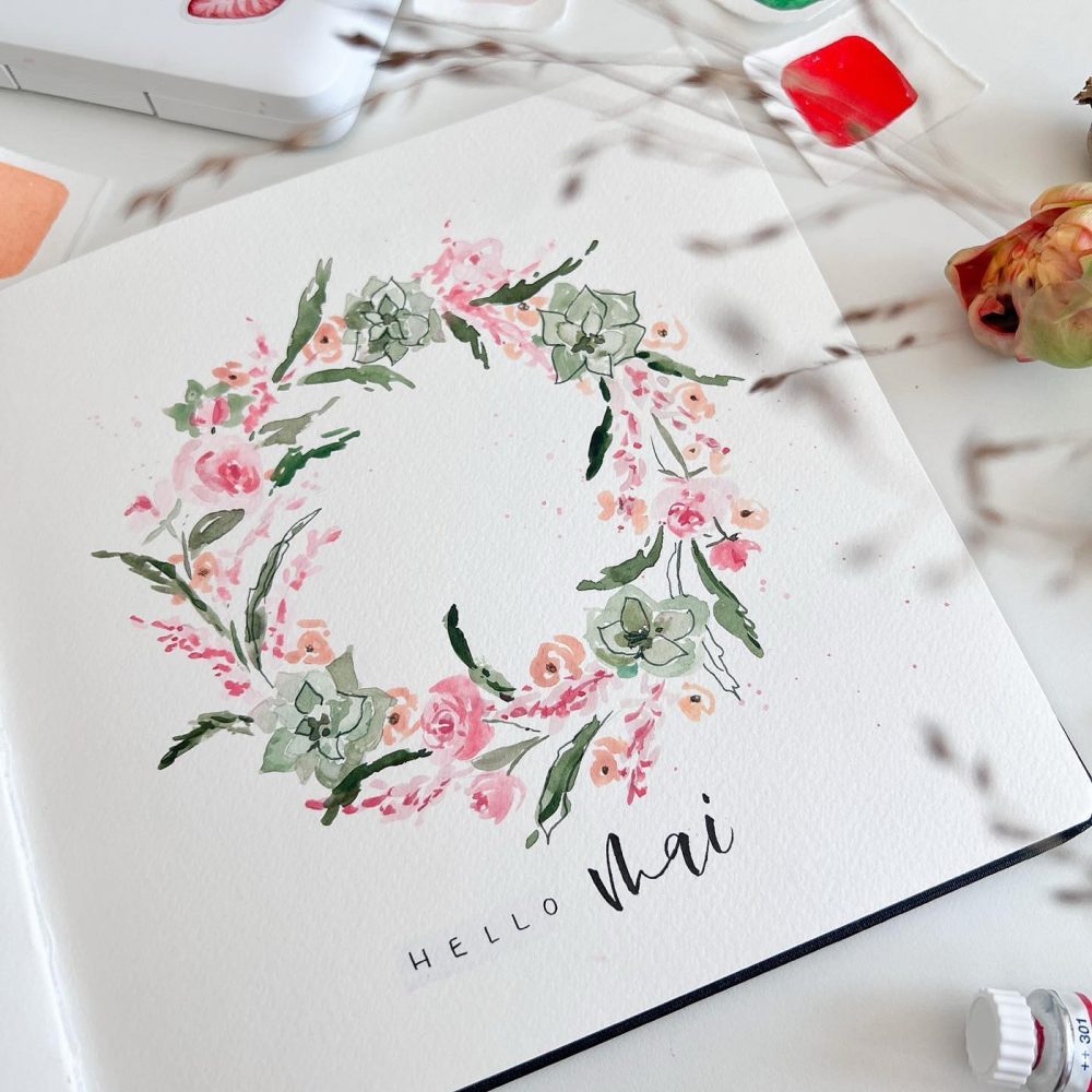 Aquarell-Blumenkranz mit dem Schriftzug Hello Mai